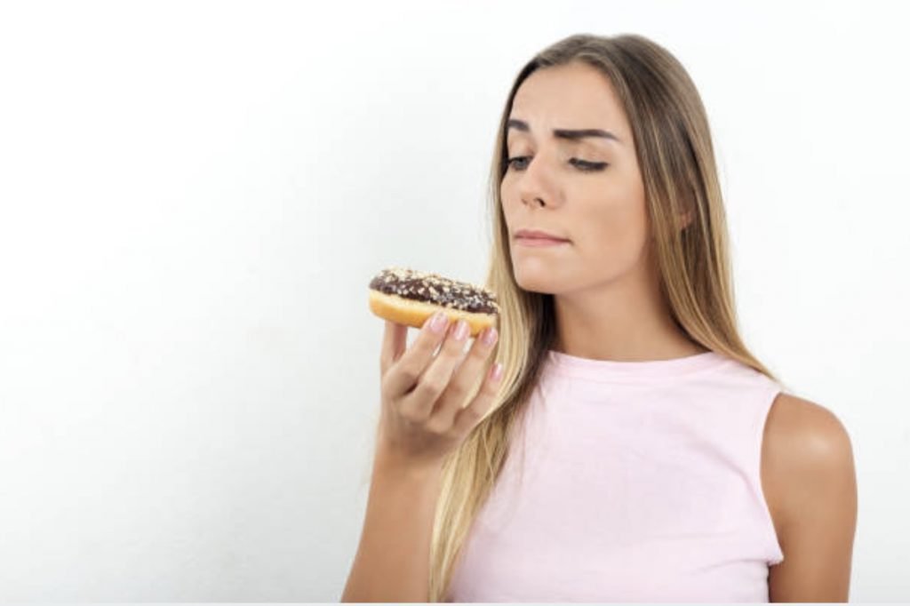 a girl thinking of eating a donut